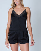 Woman wearing a black lace-trimmed camisole and shorts set against a light gray background