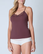 Woman wearing a chocolate soft seamless  lace-trimmed camisole against a light gray background