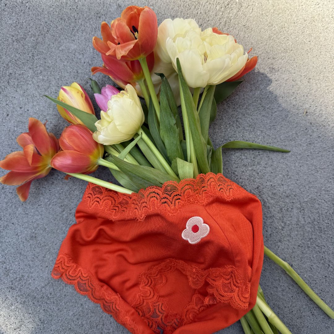Uwila Warrior Spicy Orange Soft Silk Briefs with a floral arrangement