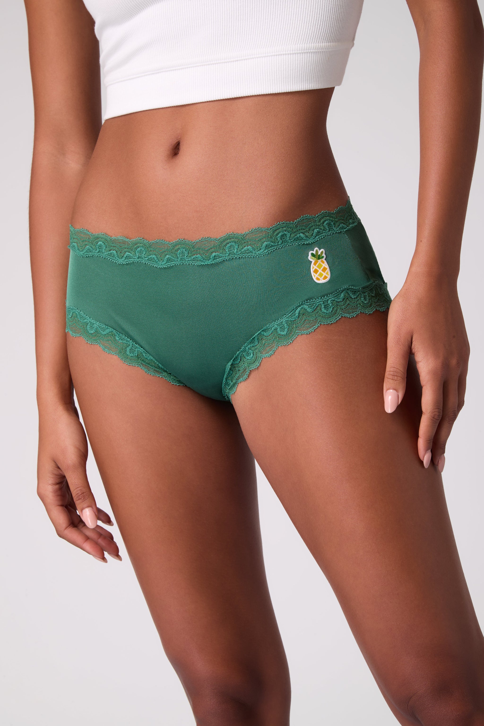 Model wearing Uwila Warrior Smoke Pine Soft Silk Briefs with Embroidered pineapple patch.
