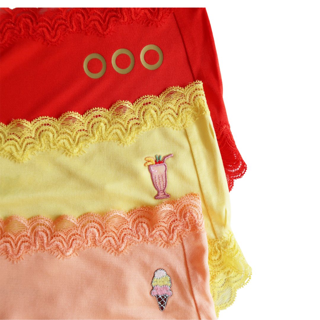 Close-up of a red, yellow, and peach fabric with lace details and embroidered designs.