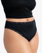 Model wearing Uwila Warrior Soft Silks Thong Underwear in Tap Shoe Black on White Background