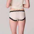 Back view of model wearing a Soft Silk winter white brief with contrasting tap shoe black lace on a white background. 
