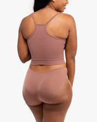 A woman wearing Toffee bralette with thin straps and a ribbed texture with toffee briefs on white background.