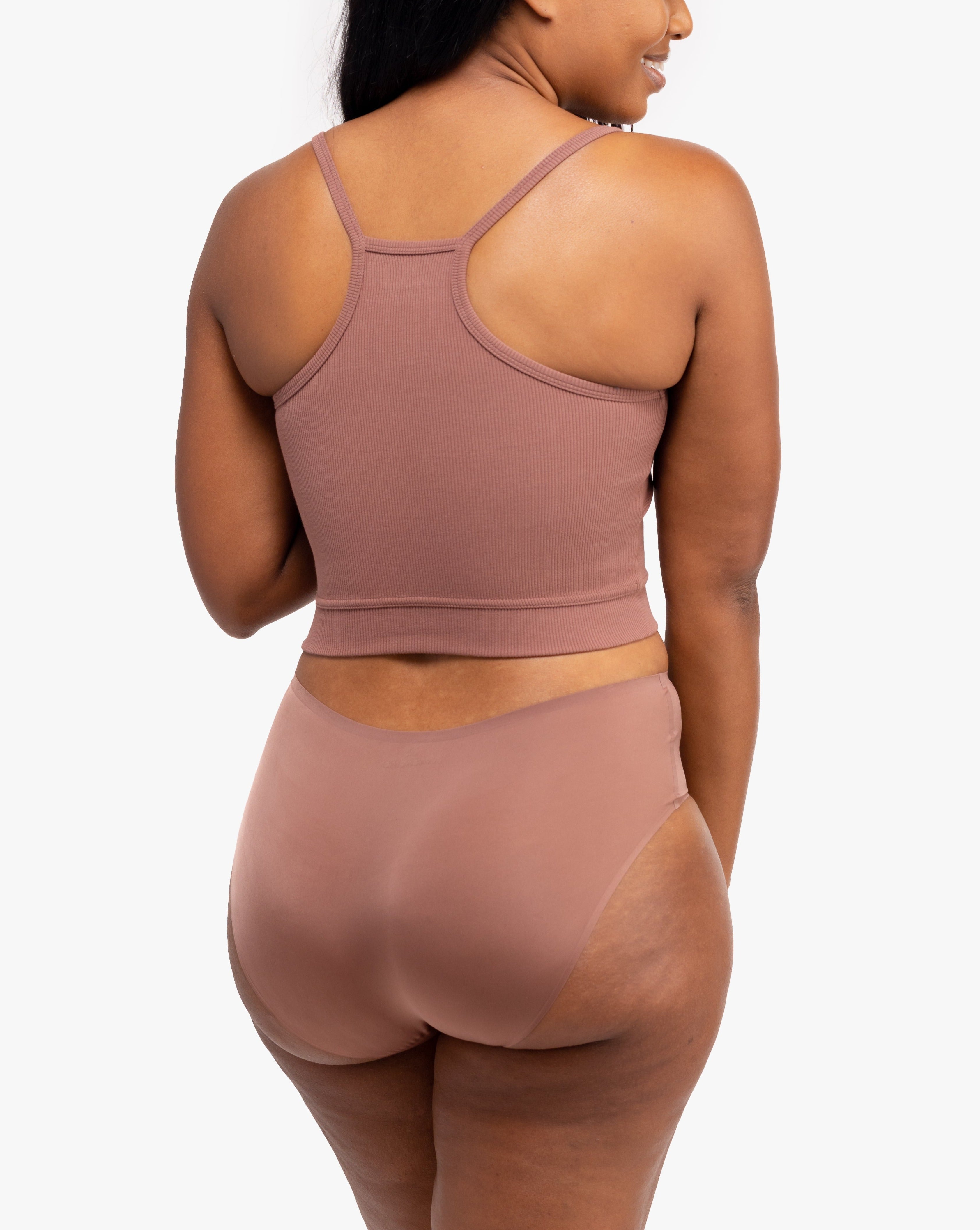 A woman wearing Toffee bralette with thin straps and a ribbed texture with toffee briefs on white background.