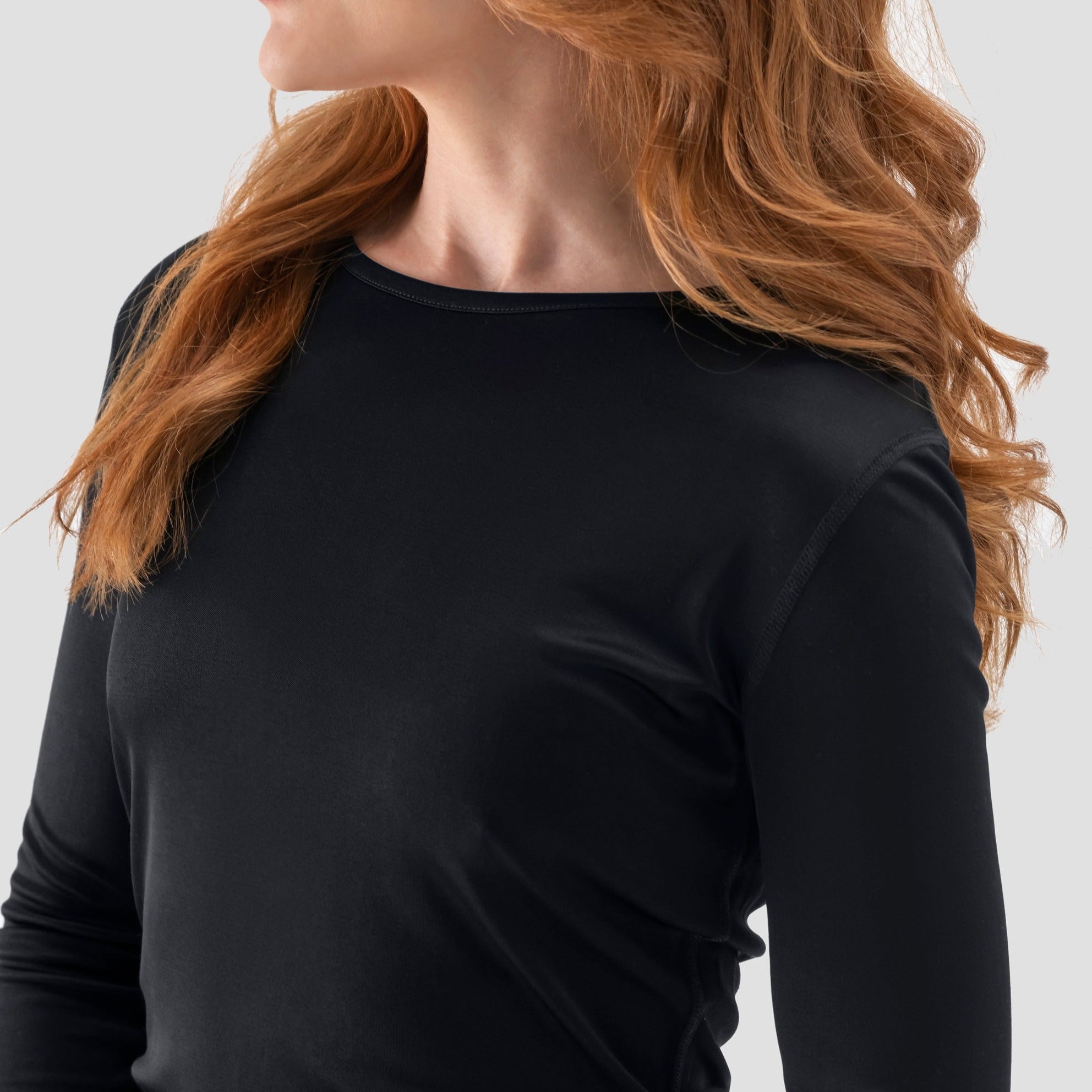 A model wearing a long-sleeve  Tap Shoe Black base layer T-shirt by Uwila Warrior, shown in a against a white background.