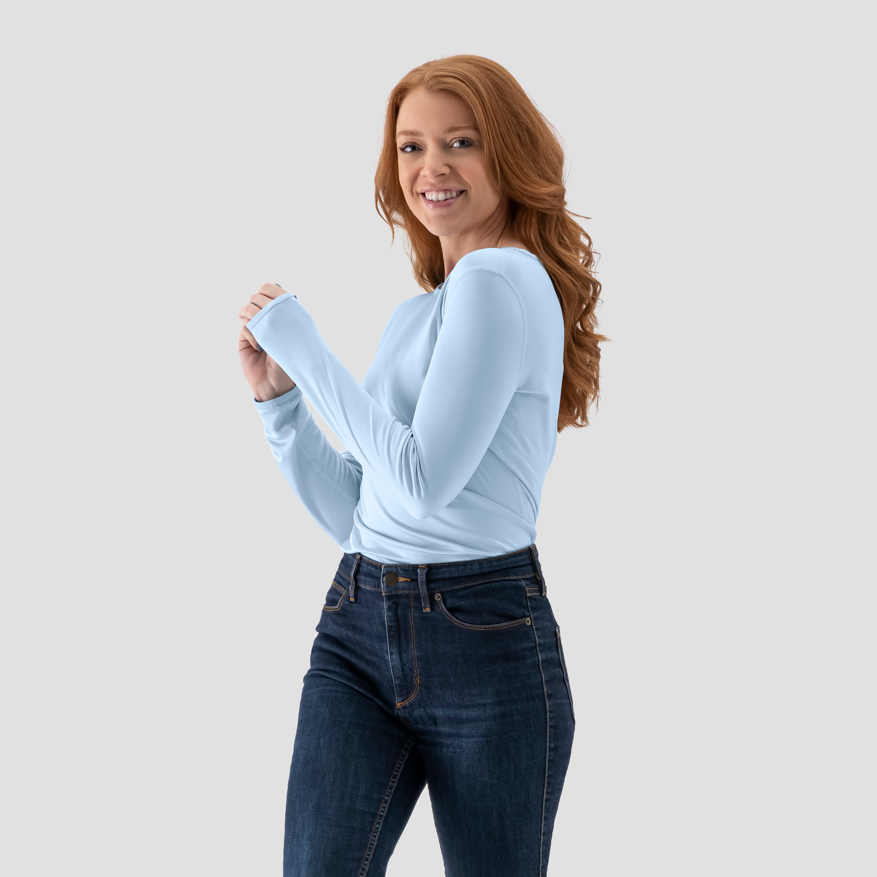 Modeling wearing a long-sleeve Ice Blue base layer T-shirt by Uwila Warrior, shown against a white background.