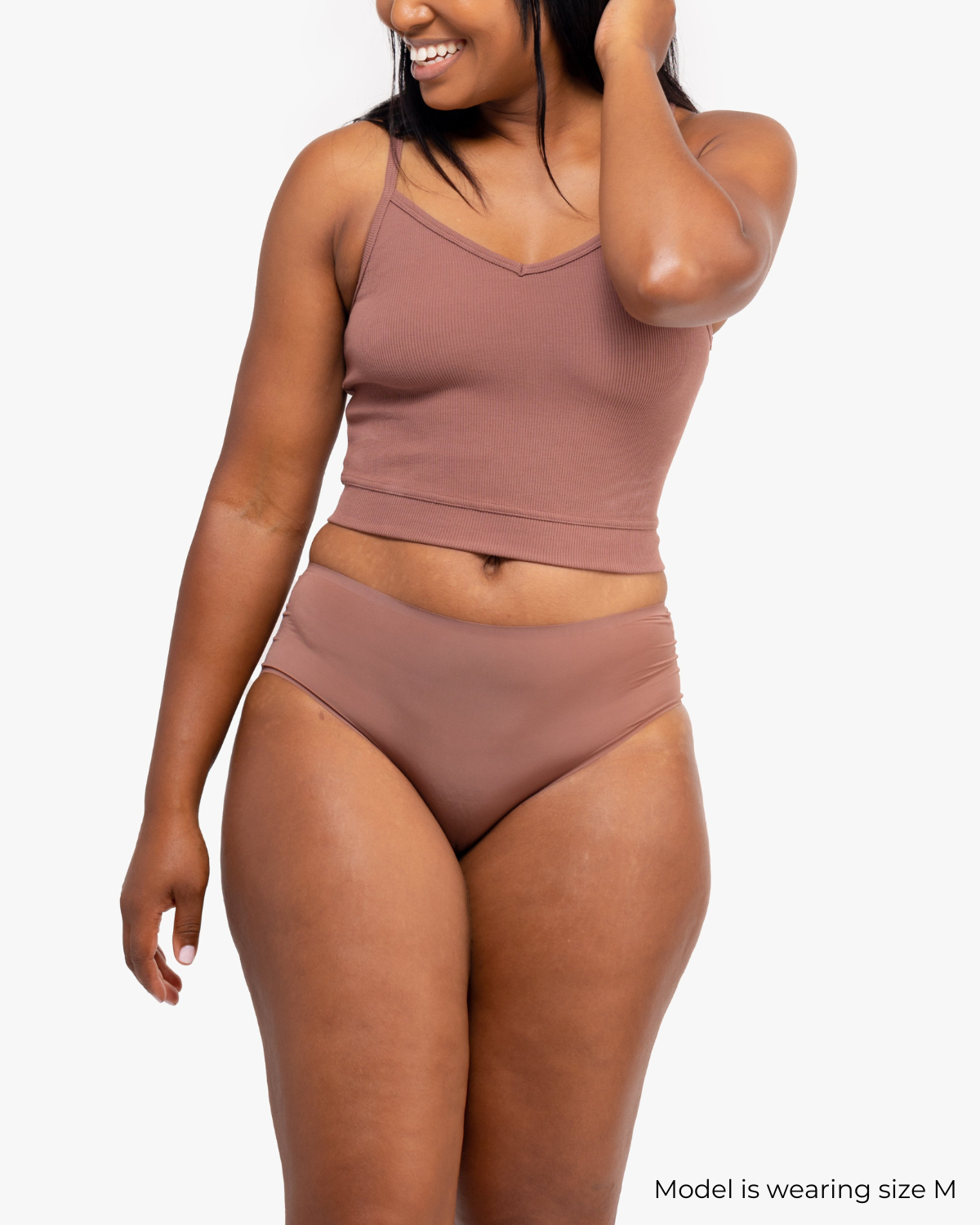 A woman wearing Toffee bralette with thin straps and a ribbed texture with toffee briefs on white background.