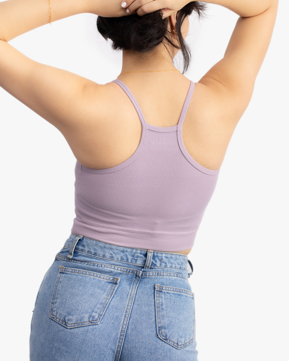 A woman wearing a nirvana bralette with thin straps and a ribbed texture on white background.