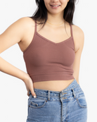 A woman wearing Toffee bralette with thin straps and a ribbed texture with jeans on white background.